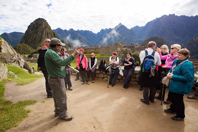 Eine viventura Gruppe lässt sich von einem erfahrenen Führer über den magischen Ort Machu Picchu aufklären.